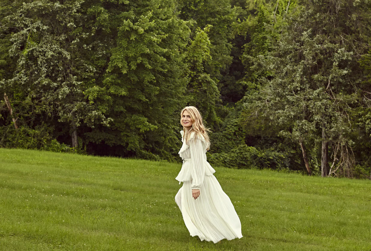 Dr. Macrene Alexiades walking across a green lawn in a long white dress