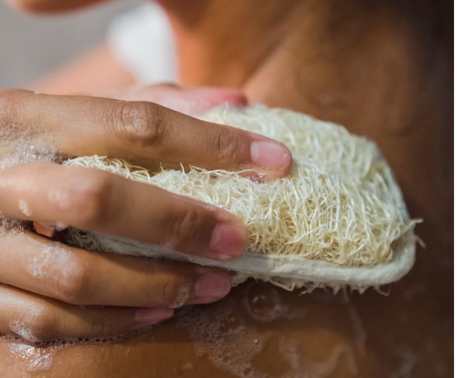 woman exfoliating body with loofah