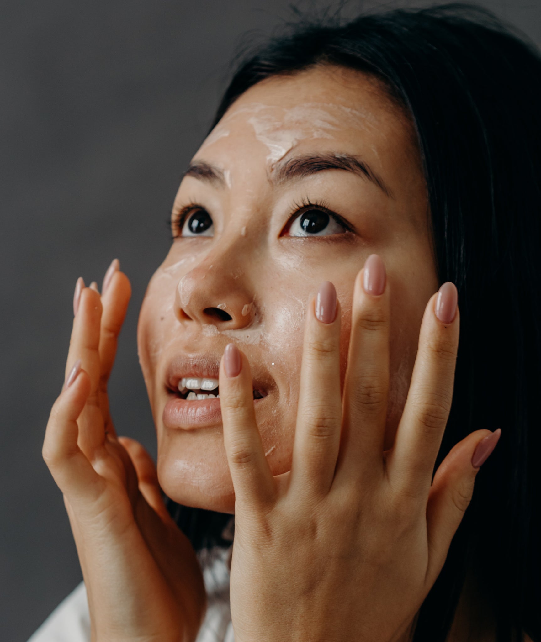 woman applying a skincare product to her face with both hands