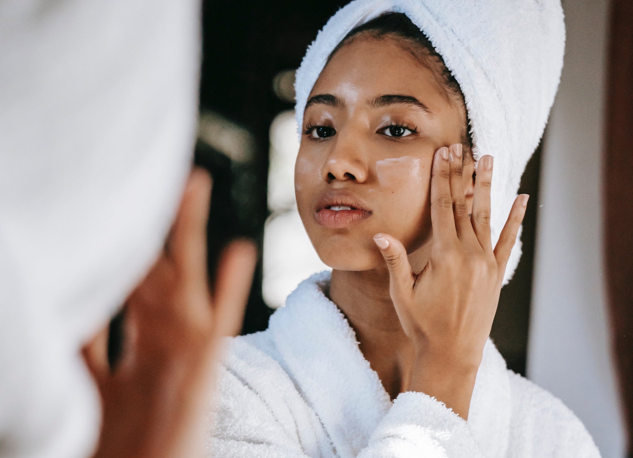 woman in a hair towel applying face cream